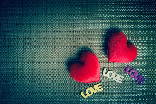 Два красных сердца и текст "ЛЮБОВЬ" на фоне текстуры — стоковое фото