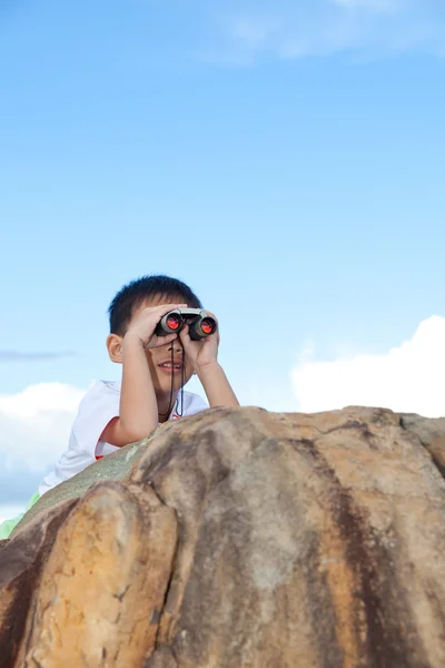 Menino feliz explorando ao ar livre clambering em uma rocha com te — Fotografia de Stock