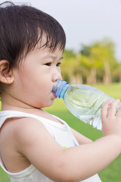 Weinig Aziatische meisje drinkwater uit plastic fles — Stockfoto