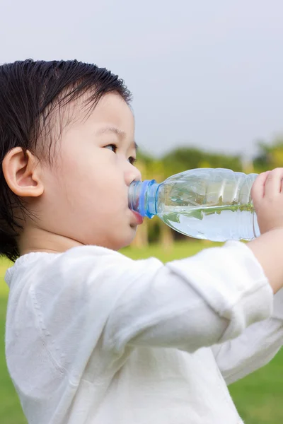 Weinig Aziatische meisje drinkwater uit plastic fles — Stockfoto