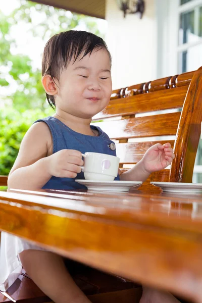 Malá Asijská dívka usmívá a drží sklenici vody — Stock fotografie