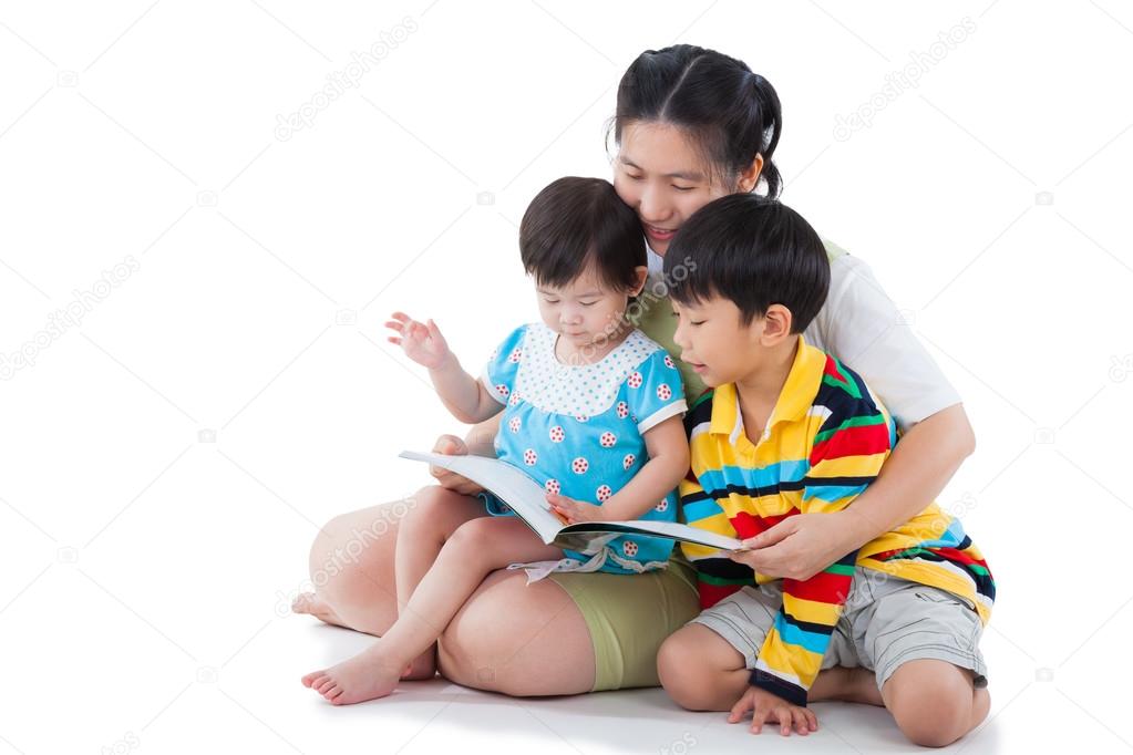 Young female with two little asian children reading a book