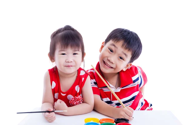 Children looking at the camera and smiling, holding a paintbrush — Stock Photo, Image