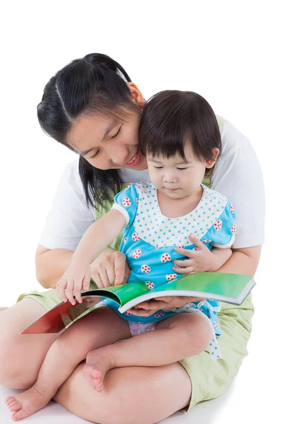 Young female with little asian girl reading a book — Stock Photo, Image