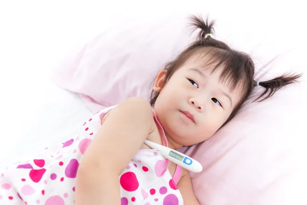 Mała dziewczynka leżąc na łóżko chorego z cyfrowy termometr w jej ramię — Zdjęcie stockowe