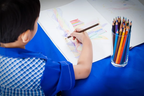 Pequeño asiático chico sentado a la mesa y dibujo por color penc —  Fotos de Stock