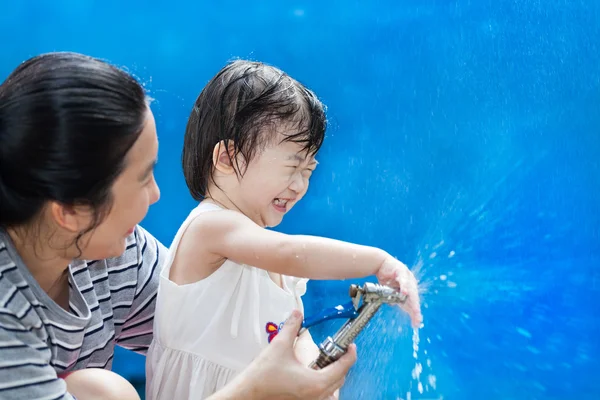 Pequeña chica asiática y madre jugar con manguera de agua — Foto de Stock