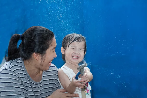 Küçük Asyalı kız ve annesi su hortumu ile oynamak — Stok fotoğraf