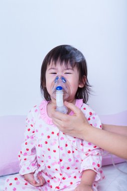 Doktor inhalasyon için küçük kız yardımcı olur.