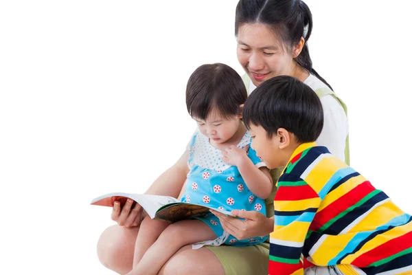 Jeune femme avec deux petits enfants asiatiques lisant un livre Photos De Stock Libres De Droits