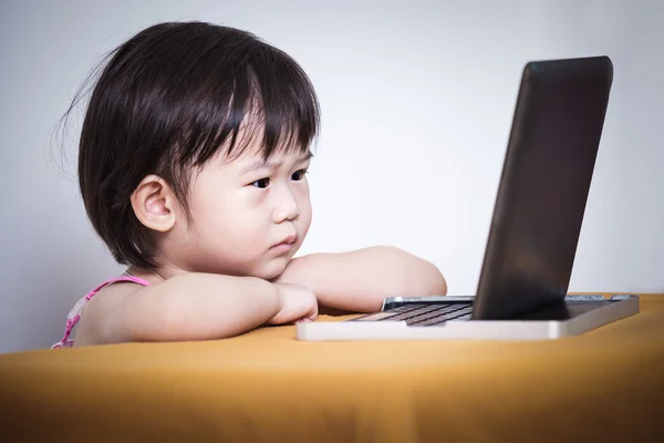 Bambino serio seduto e alla ricerca di una storia su touchscreen digitale Immagine Stock