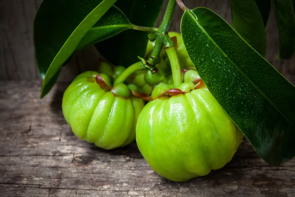 Stilleven met verse garcinia cambogia op houten achtergrond — Stockfoto