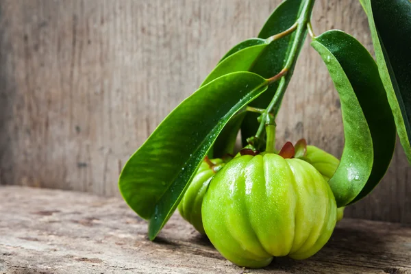 Still life with fresh garcinia cambogia on wooden background — Stock Photo, Image