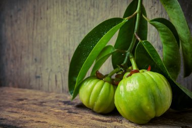 Still life with fresh garcinia cambogia on wooden background (Th clipart