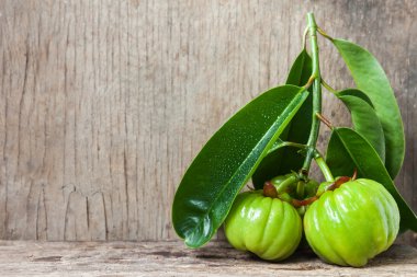 Still life with fresh garcinia cambogia on wooden background clipart