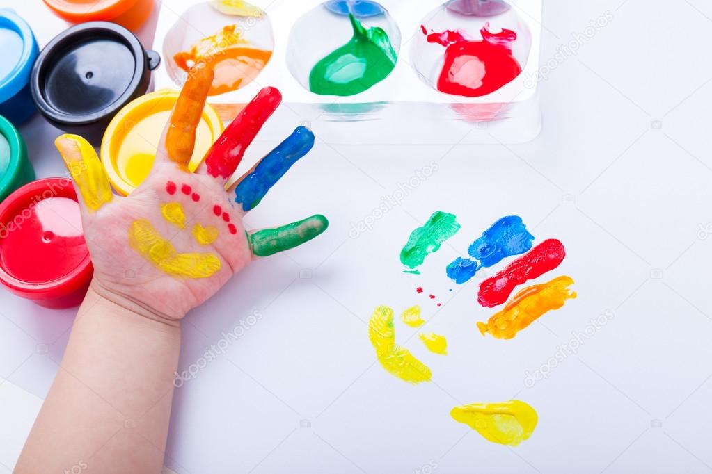 Child paint her palm with smiling face various colors. Studio sh