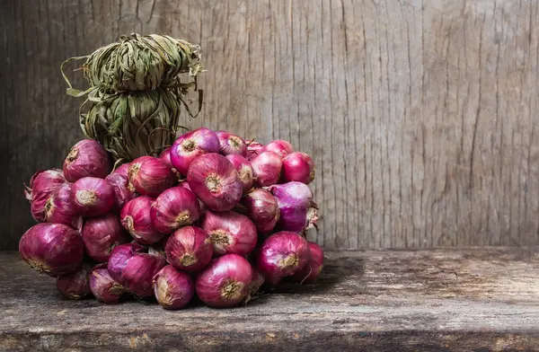 Bunch of fresh red onions on old wooden background — Stock Photo, Image