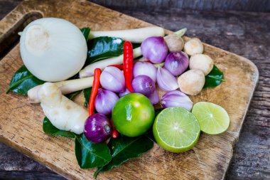 Güney Afrika'da bir kabile kireç yaprak, limon, limon, havlıcan, biber, soğan ve saman mantar bitki ve maddeler baharatlı Tayland yemekleri (tom yum) ahşap arka plan üzerinde kesme blok üzerinde.