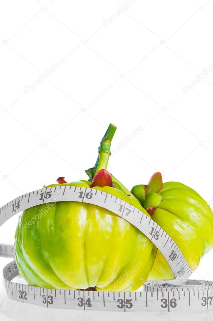 Garcinia cambogia with measuring tape, isolated on white background