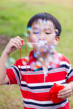 Asyalı çocuk yaz park, doğa kağıt sabun köpüğü üfleme