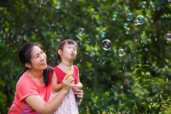 Asian lovely girl and her mother blowing soap bubbles. Family in Park — Stock Photo, Image