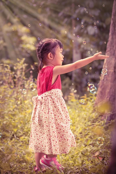 Asian girl catches soap bubbles on nature background. Outdoors. — Stock Photo, Image