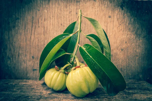 Garcinia cambogia fresca sobre fondo de madera. Tono vintage . — Foto de Stock