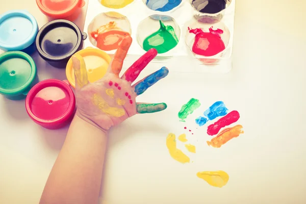 Bambino dipingere il palmo della mano con volto sorridente vari colori. Studio sparare — Foto Stock