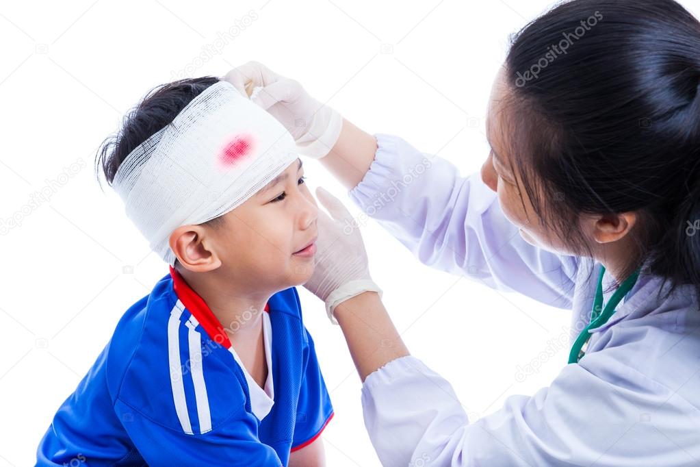 Sports injury. Doctor makes a bandage on head patient, on white.
