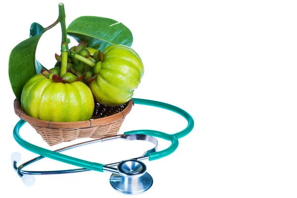 Primer plano garcinia cambogia y estetoscopio sobre fondo blanco . — Foto de Stock