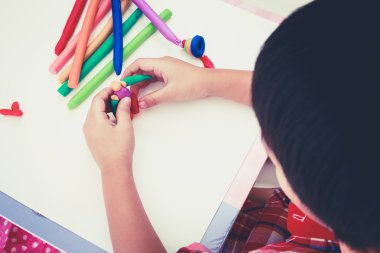 Child moulding whale modeling clay, on white background. Strengthen the imagination of child. Retro picture style.