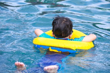 Arkadan görünüşü Havuzda yüzmek tüp ile Asya çocuk. Açık. 