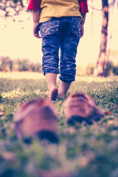 La chica se quita los zapatos. El pie del niño aprende a caminar sobre la hierba — Foto de Stock