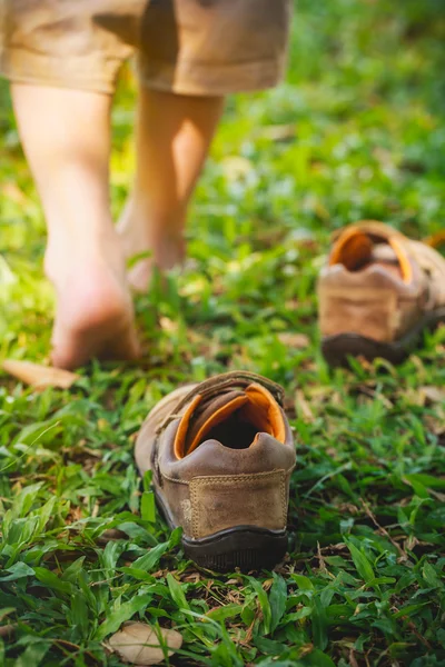 Il bambino si toglie le scarpe. Il piede del bambino impara a camminare sull'erba — Foto Stock