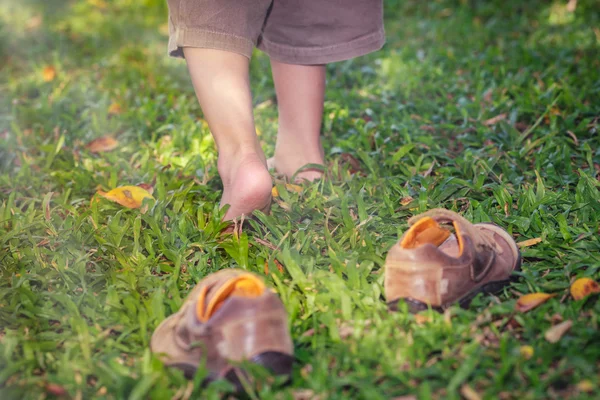 A criança tira os sapatos. Pé de criança aprende a andar na grama — Fotografia de Stock