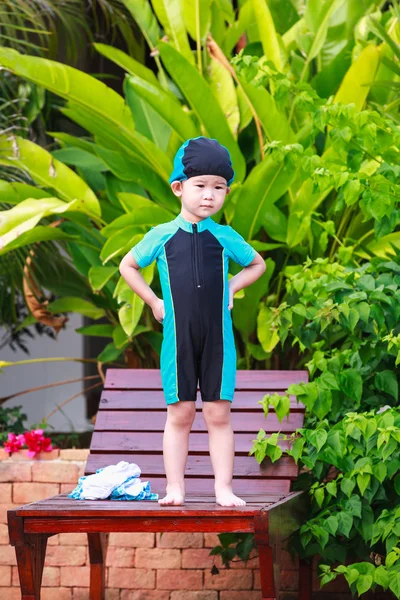 Cute little asian girl in swimsuit standing on relaxing chair. Outdoors. — Stok fotoğraf