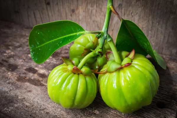 Stilleven met verse garcinia cambogia op houten achtergrond — Stockfoto