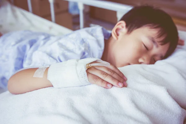 Asiatischer Junge schläft auf dem Krankenbett, intravenöse Kochsalzlösung (iv) auf der Hand. — Stockfoto