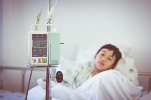 Ασιατικές αγόρι που βρίσκεται σε sickbed με έγχυση αντλία στάγδην ενδοφλέβια Iv — Φωτογραφία Αρχείου