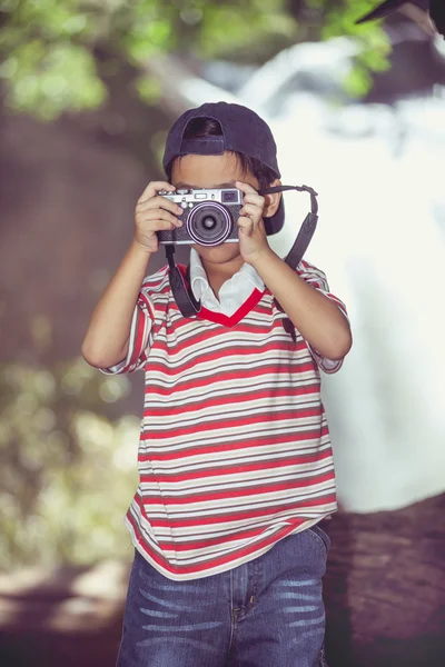 Aziatische jongen fotograaf met de Camera In de prachtige waterval. Retro stijl. — Stockfoto