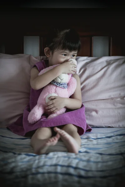 Little sad asian girl sitting on bed. Vignette picture style. — Stock Photo, Image