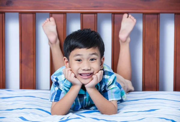 Retrato de chico guapo acostado descalzo en la cama en el dormitorio . —  Fotos de Stock