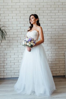 Beyaz gelinlik içinde bir buketle güzel bir gelinin portresi