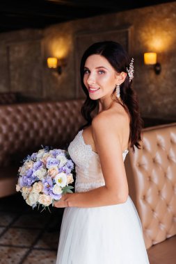 Beyaz gelinlik içinde bir buketle güzel bir gelinin portresi