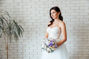 Beyaz gelinlik içinde bir buketle güzel bir gelinin portresi