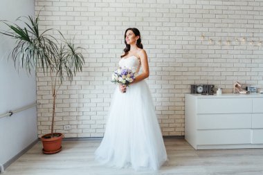 Beyaz gelinlik içinde bir buketle güzel bir gelinin portresi