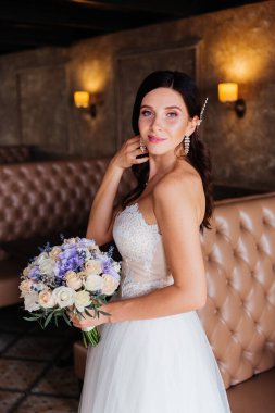 Beyaz gelinlik içinde bir buketle güzel bir gelinin portresi