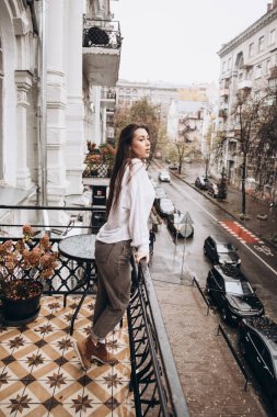 Balkonda beyaz gömlekli güzel bir kızın fotoğrafı.