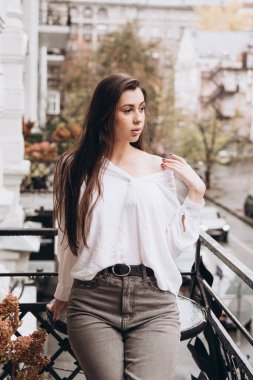 Balkonda beyaz gömlekli güzel bir kızın fotoğrafı.