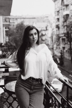 Balkonda beyaz gömlekli güzel bir kızın fotoğrafı.